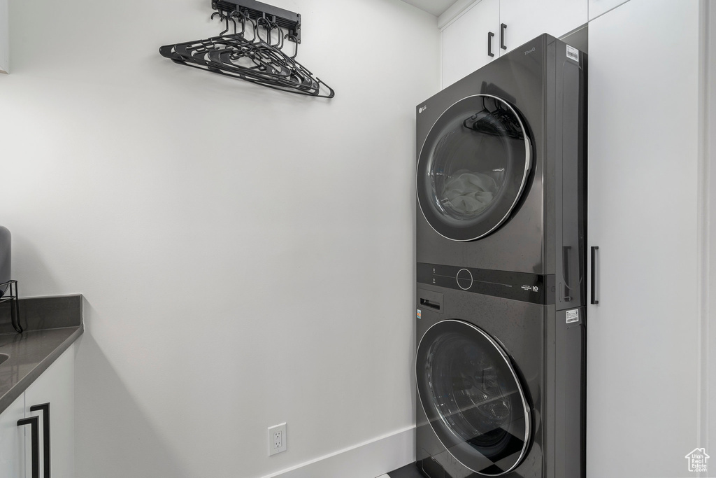 Washroom featuring cabinets and stacked washer and clothes dryer