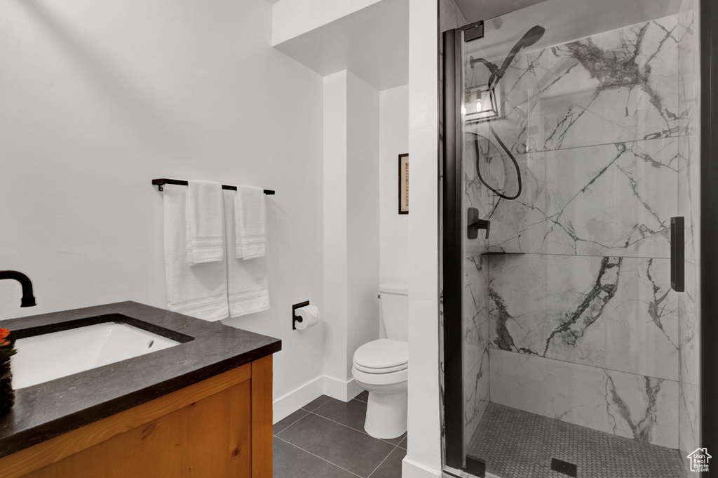 Bathroom featuring tiled shower, vanity, toilet, and tile floors