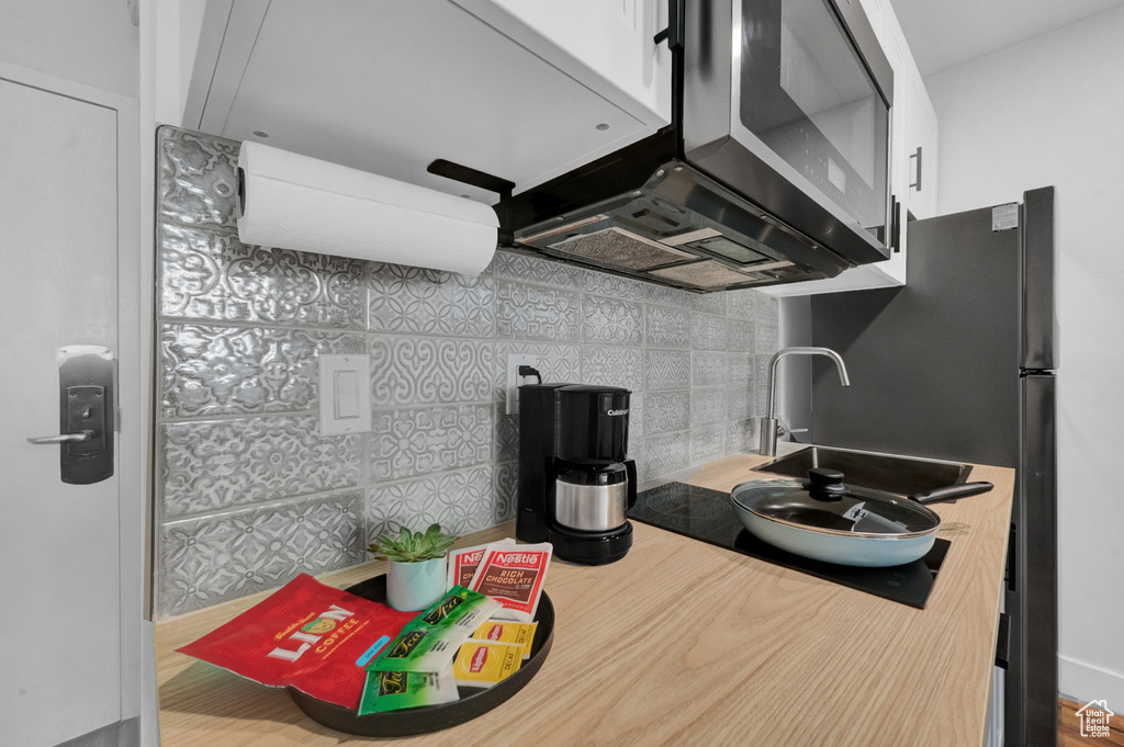 Kitchen featuring backsplash, premium range hood, and tile walls