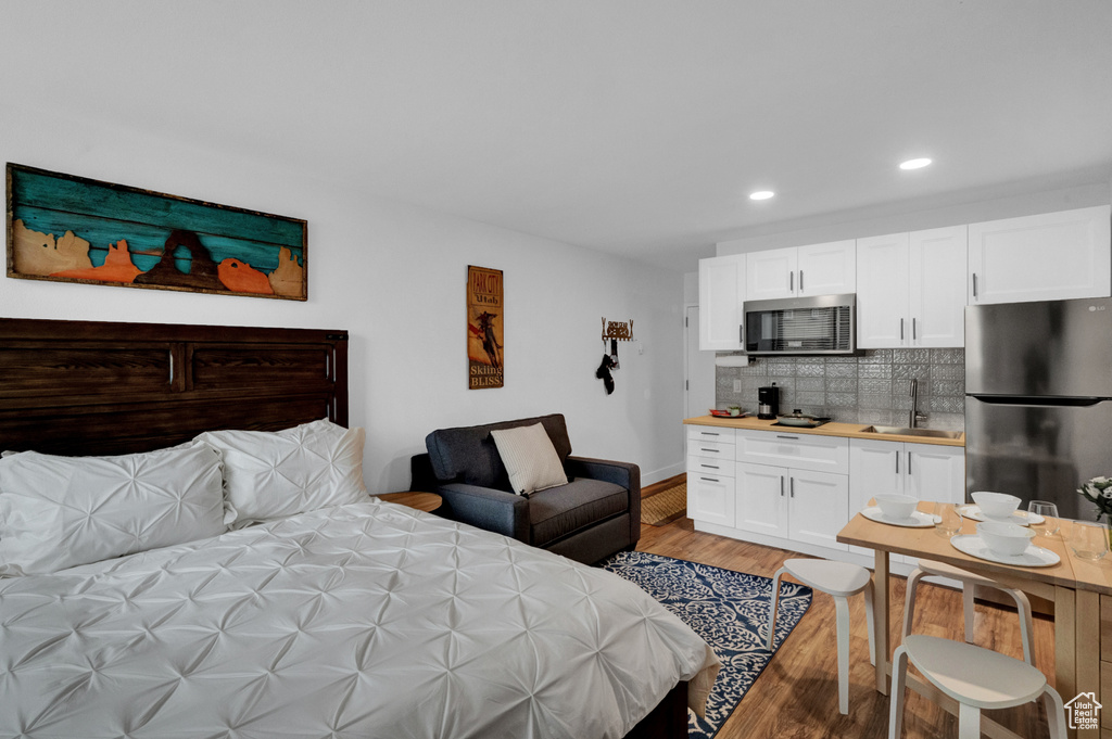 Bedroom featuring sink, light wood-type flooring, and stainless steel fridge