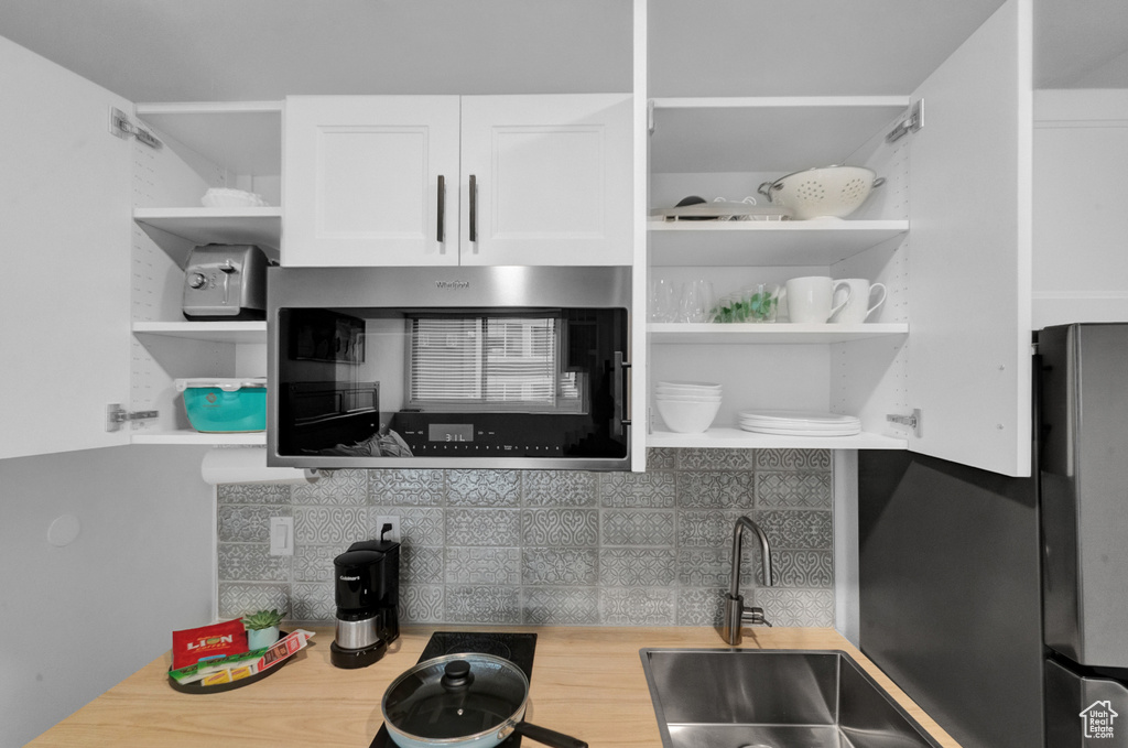 Kitchen featuring tasteful backsplash, stainless steel appliances, white cabinets, and sink