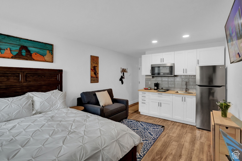 Bedroom featuring stainless steel refrigerator, light hardwood / wood-style flooring, and sink
