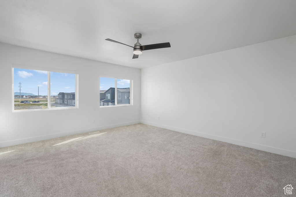 Carpeted empty room with ceiling fan and a healthy amount of sunlight