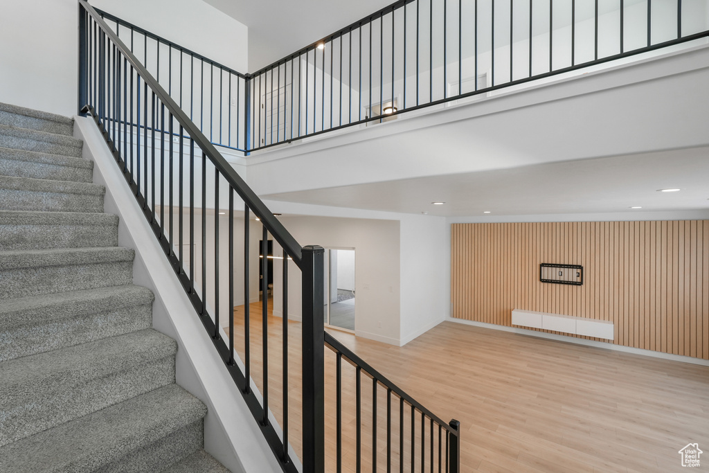 Staircase featuring light hardwood / wood-style floors, a high ceiling, and radiator heating unit