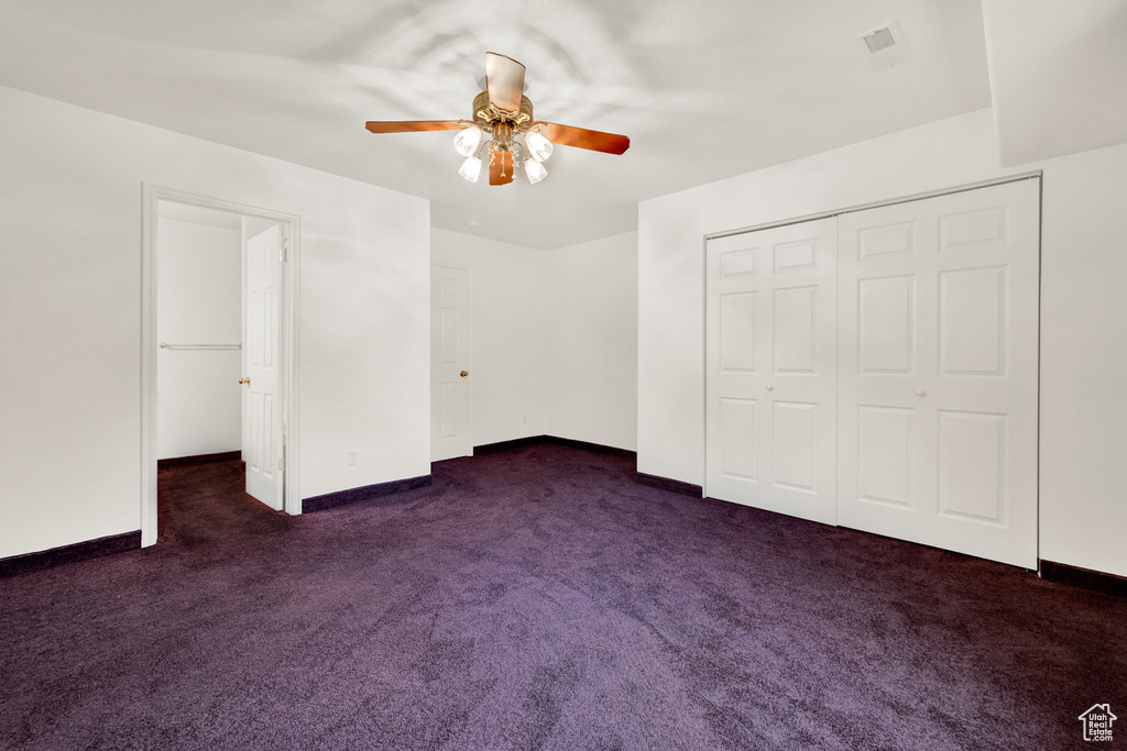Unfurnished bedroom featuring dark colored carpet, a closet, and ceiling fan