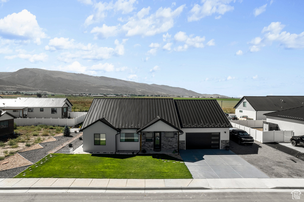 View of front of property with a front yard, a mountain view, and a garage