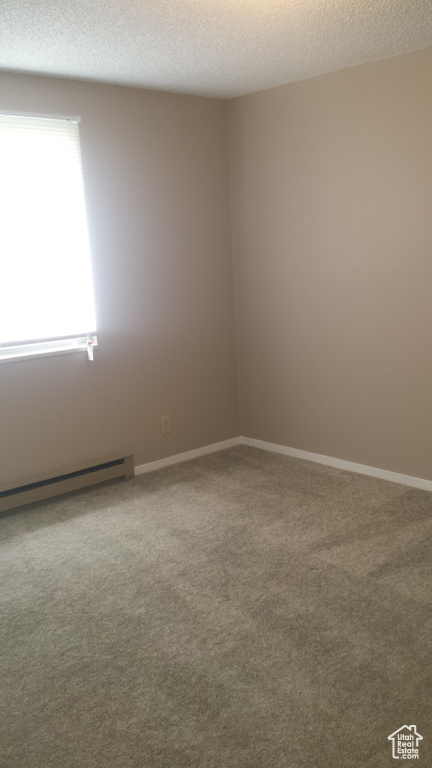 Carpeted empty room with a baseboard radiator and a textured ceiling