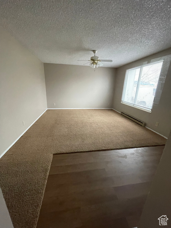 Empty room with ceiling fan, a baseboard radiator, carpet floors, and a textured ceiling
