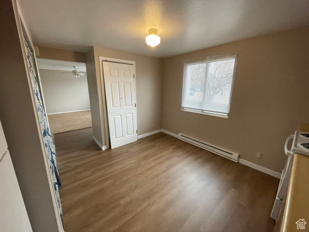 Unfurnished bedroom with a baseboard heating unit, dark hardwood / wood-style floors, and a closet