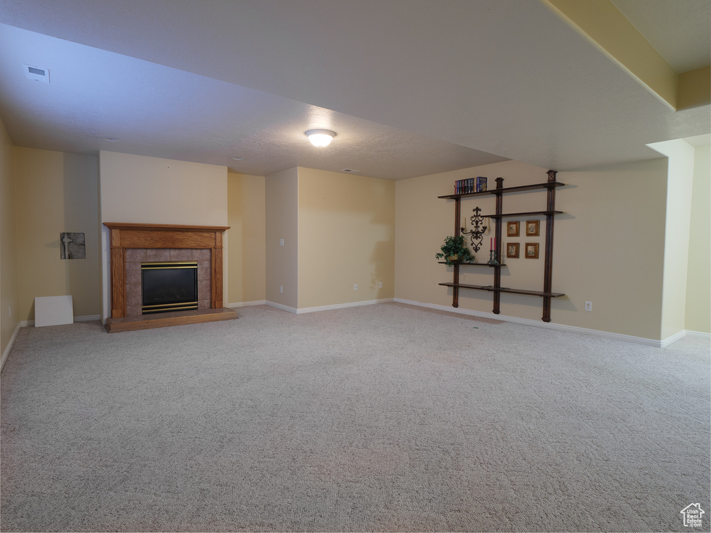 Unfurnished living room with light colored carpet and a fireplace