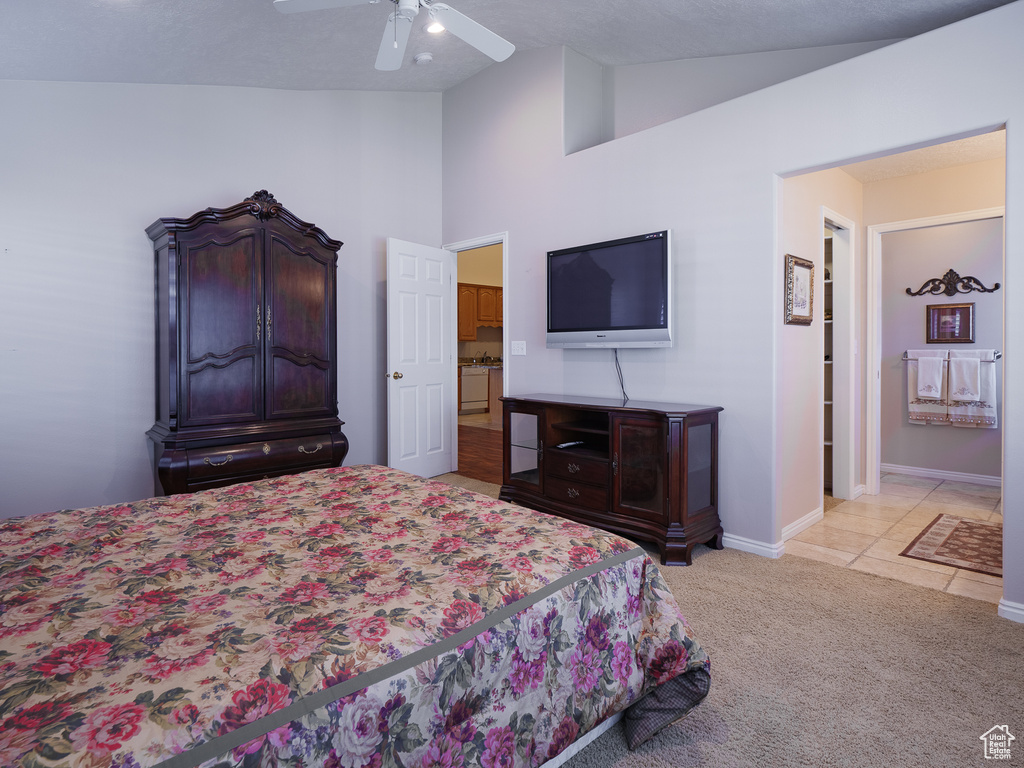 Bedroom with light colored carpet, lofted ceiling, ensuite bath, and ceiling fan