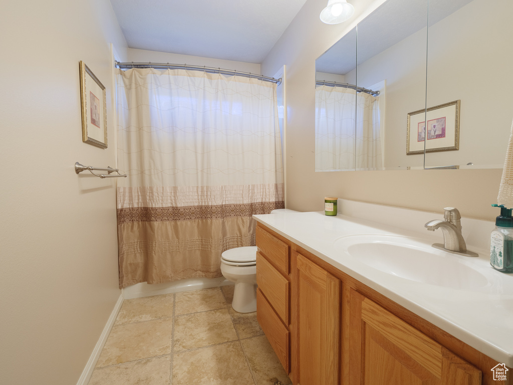 Bathroom with toilet, vanity with extensive cabinet space, and tile flooring