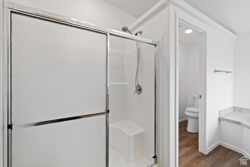 Bathroom featuring hardwood / wood-style flooring, a shower with shower door, and toilet