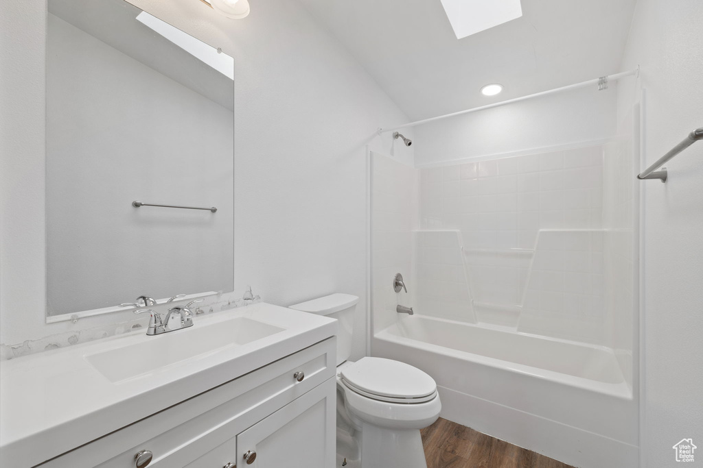 Full bathroom with a skylight, toilet, shower / bathtub combination, vanity, and hardwood / wood-style flooring
