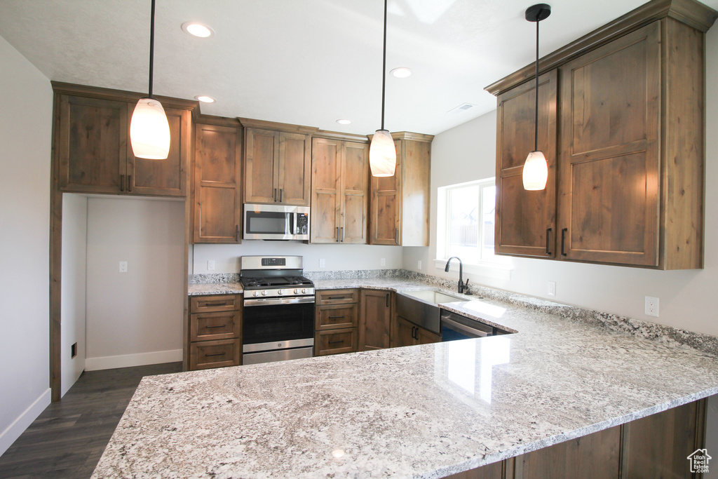 Kitchen featuring stainless steel appliances, dark hardwood / wood-style floors, sink, and decorative light fixtures