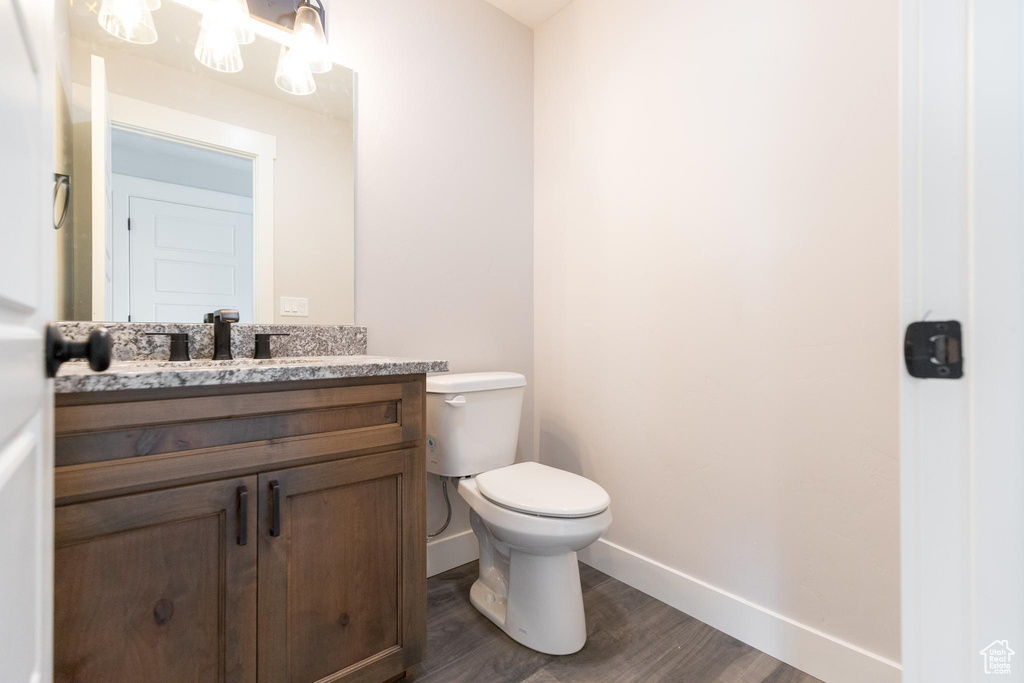 Bathroom with wood-type flooring, large vanity, and toilet