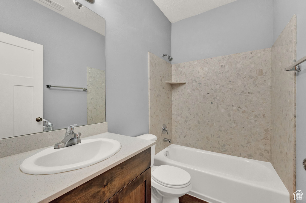 Full bathroom with vanity, a textured ceiling, shower / bathtub combination, and toilet