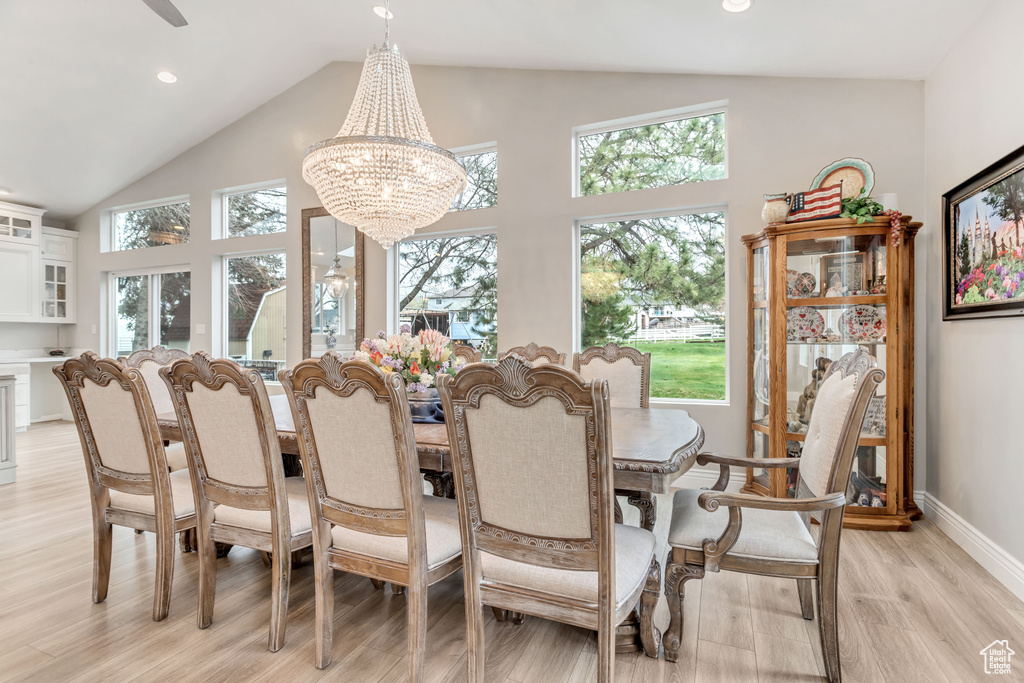 Dining room featuring high vaulted ceiling, light hardwood / wood-style flooring, a wealth of natural light, and a chandelier