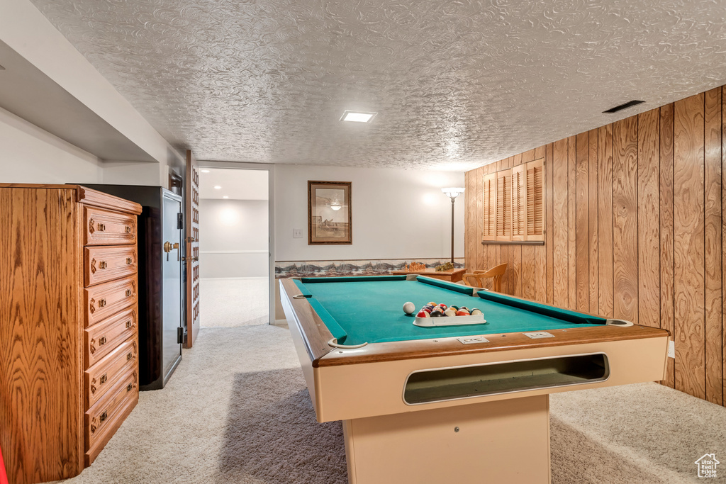 Recreation room featuring wood walls, light colored carpet, pool table, and a textured ceiling