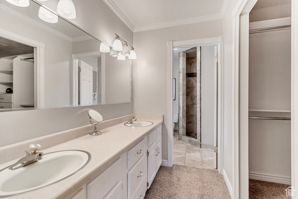 Bathroom featuring walk in shower, tile floors, ornamental molding, oversized vanity, and dual sinks