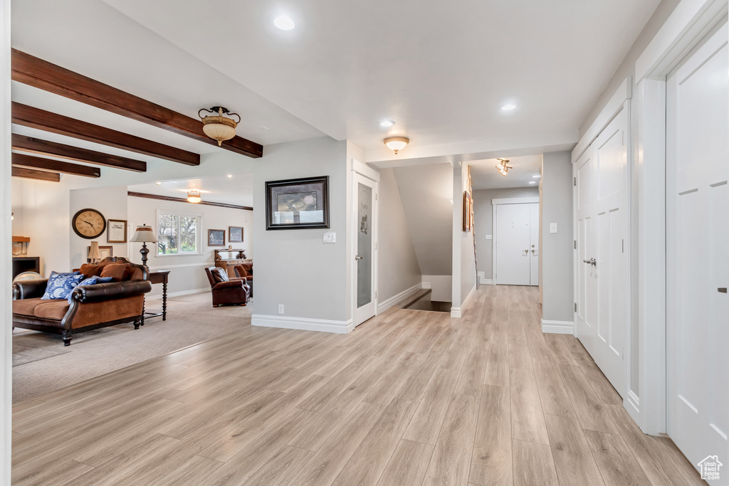 Hallway with light hardwood / wood-style floors and beam ceiling