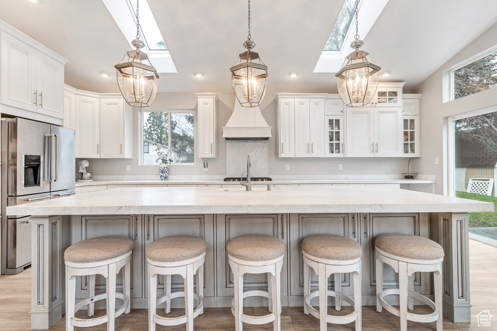 Kitchen with white cabinets, stainless steel appliances, pendant lighting, and a kitchen island with sink