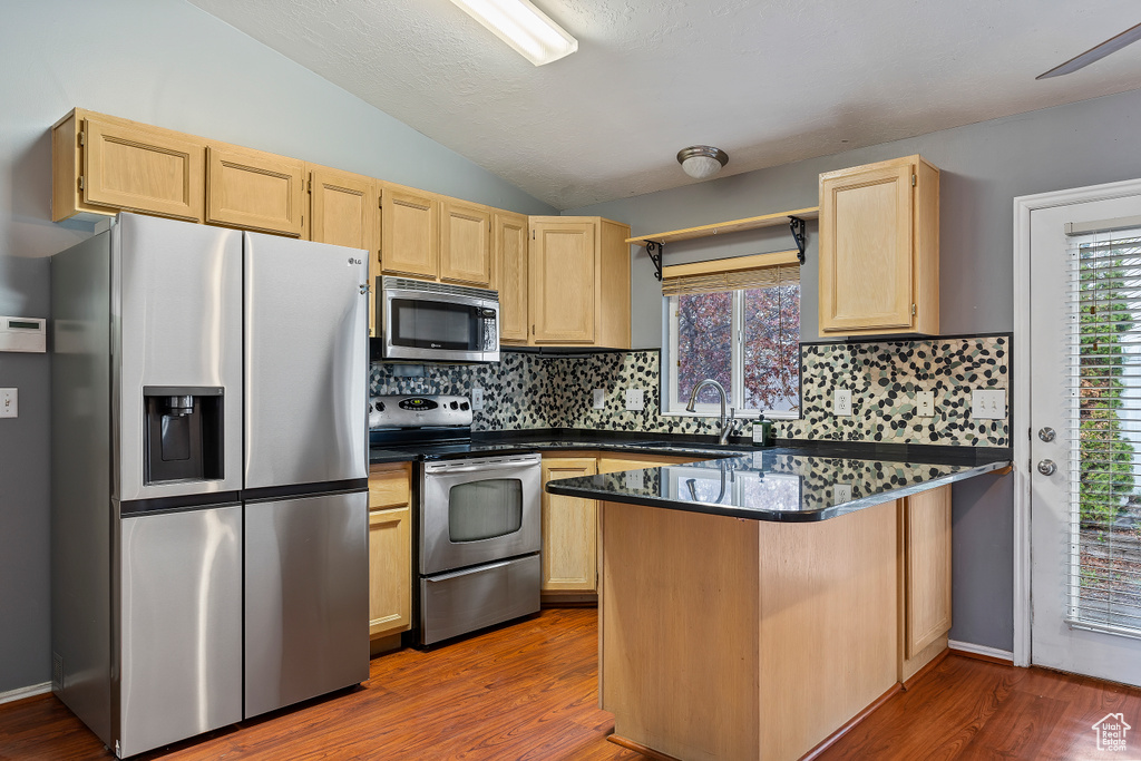 Kitchen with appliances with stainless steel finishes, tasteful backsplash, and wood-type flooring