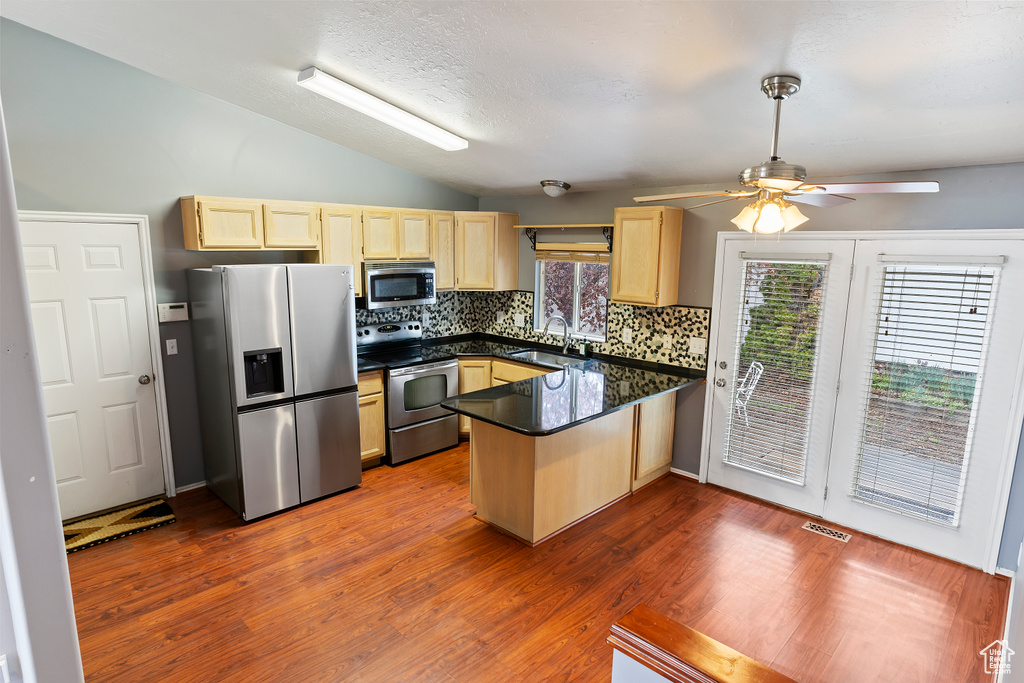 Kitchen featuring ceiling fan, stainless steel appliances, dark hardwood / wood-style floors, vaulted ceiling, and kitchen peninsula