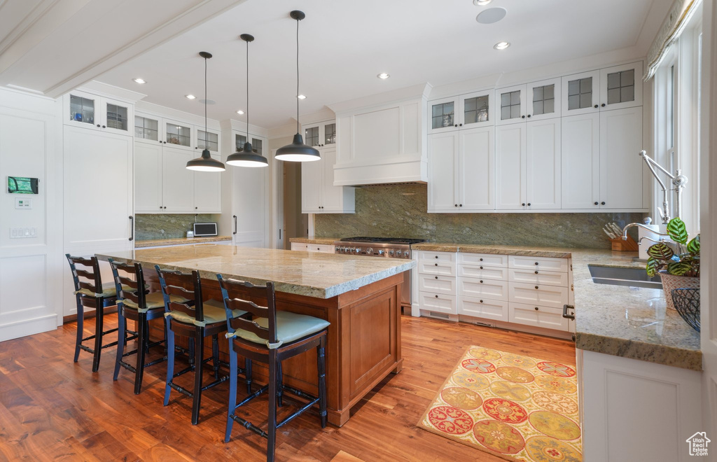 Kitchen featuring a kitchen island, light hardwood / wood-style flooring, pendant lighting, and white cabinetry
