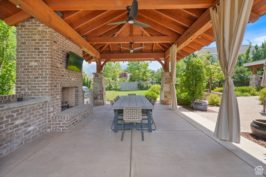 View of patio / terrace with ceiling fan, a gazebo, and an outdoor brick fireplace