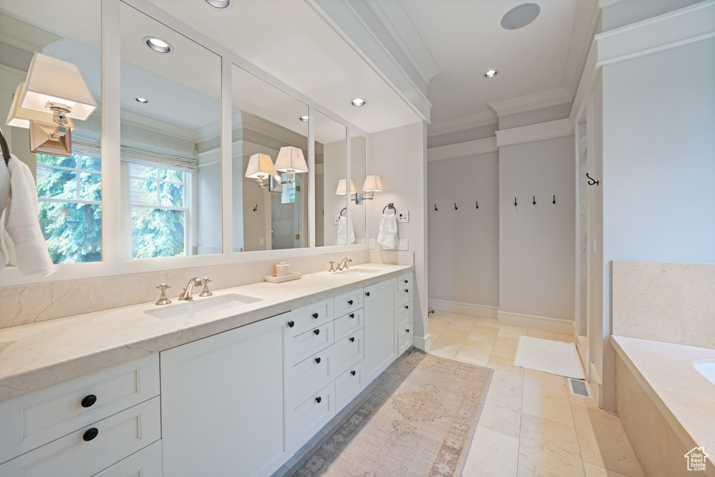 Bathroom featuring tile flooring, dual sinks, oversized vanity, tiled tub, and ornamental molding