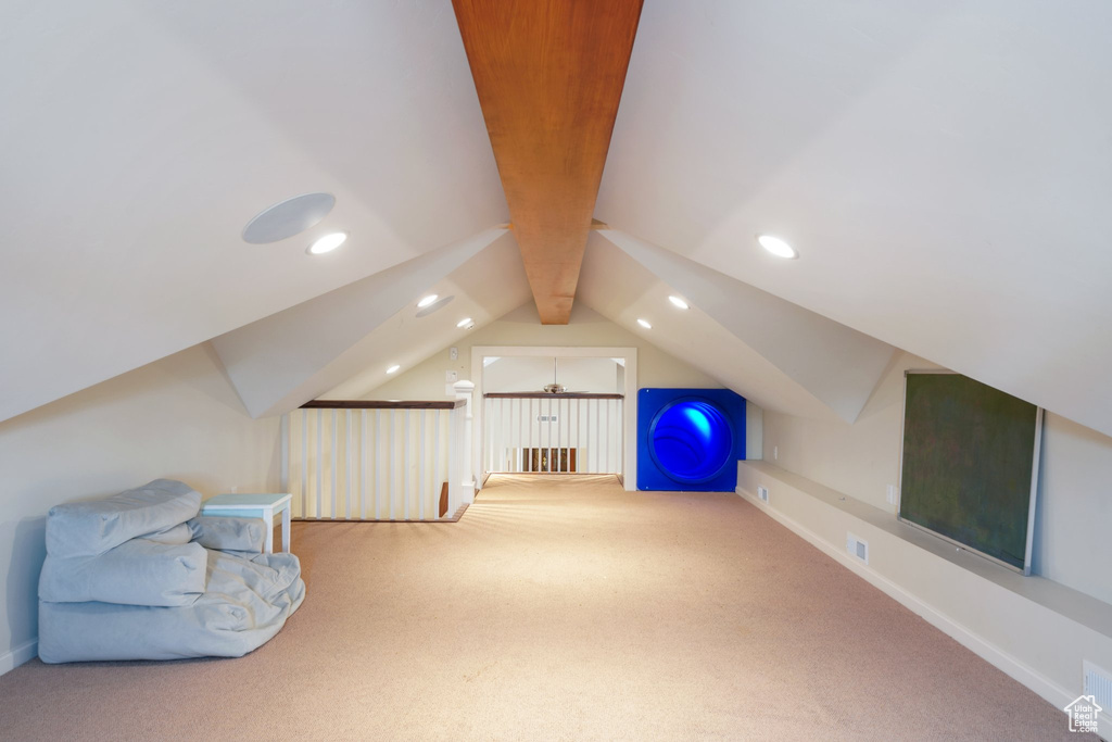 Bonus room with lofted ceiling with beams and light carpet