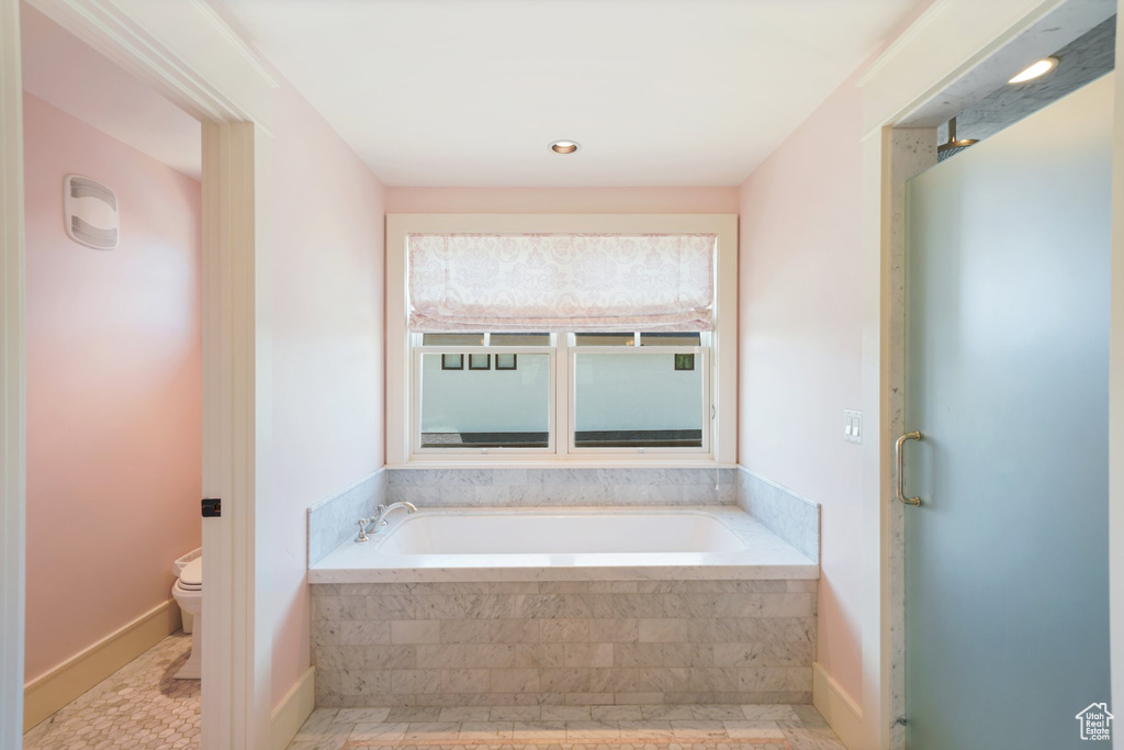 Bathroom featuring tile floors, tiled tub, and toilet