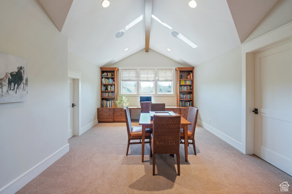 Carpeted dining room featuring vaulted ceiling with beams