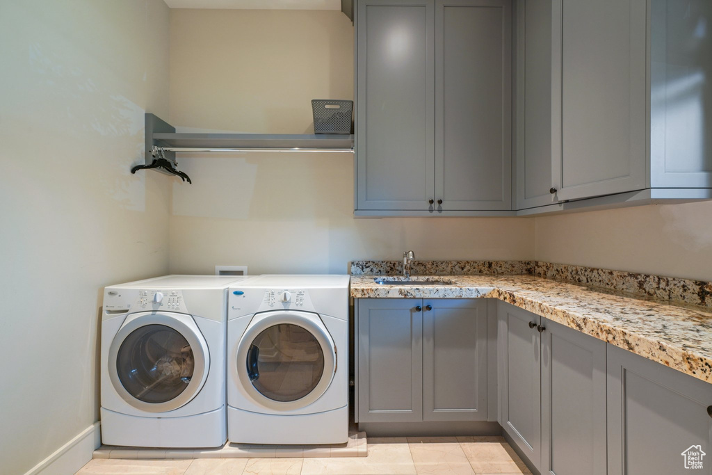 Laundry room with sink, cabinets, light tile floors, and washer and clothes dryer