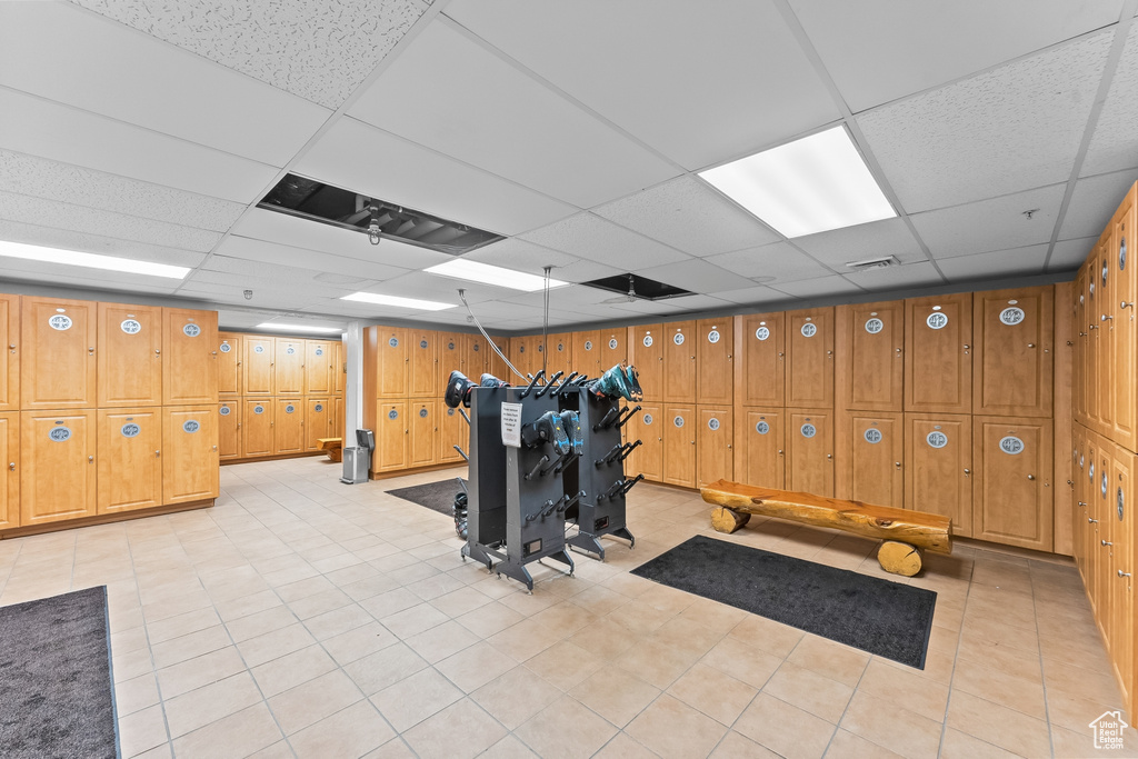 Workout area with wood walls, light tile floors, and a paneled ceiling