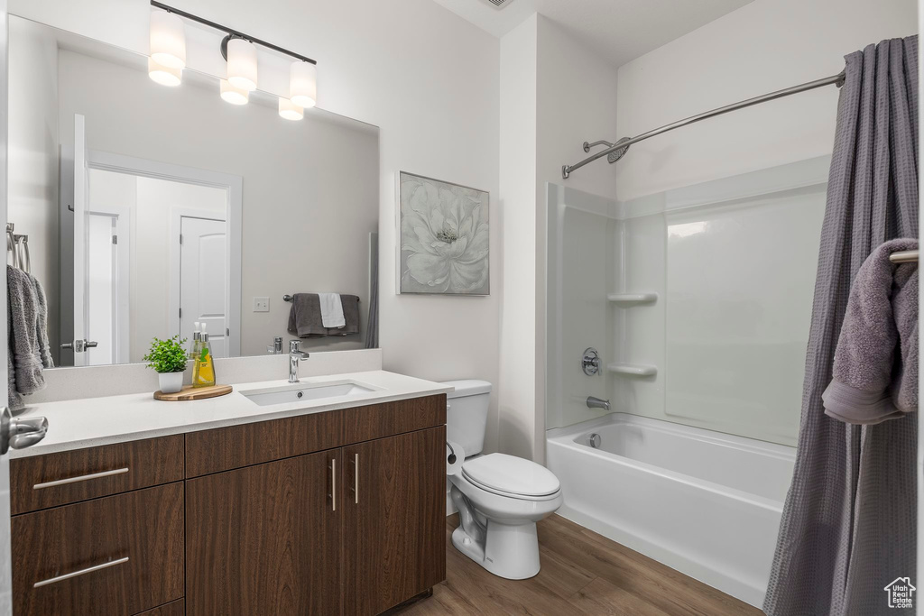 Full bathroom featuring vanity, wood-type flooring, shower / tub combo, and toilet