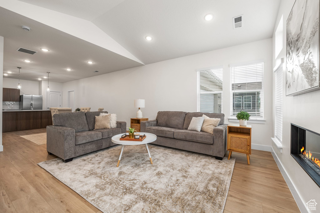 Living room with light hardwood / wood-style floors and vaulted ceiling