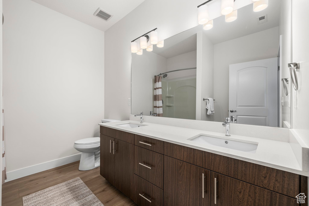 Bathroom with a shower with curtain, hardwood / wood-style floors, vanity, and toilet