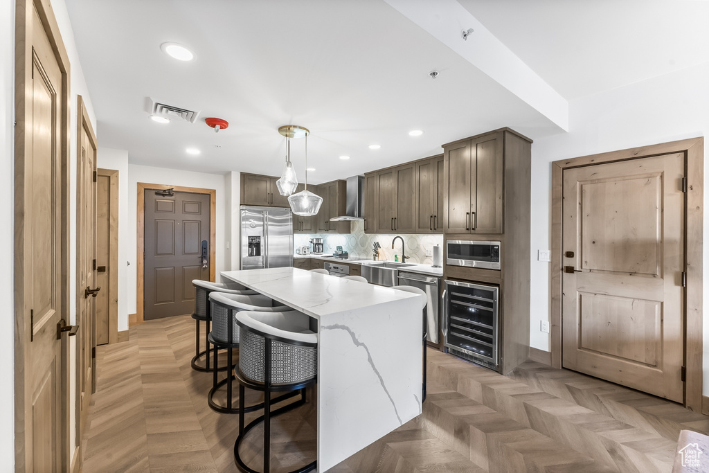 Kitchen with a kitchen island, light parquet flooring, hanging light fixtures, and stainless steel appliances