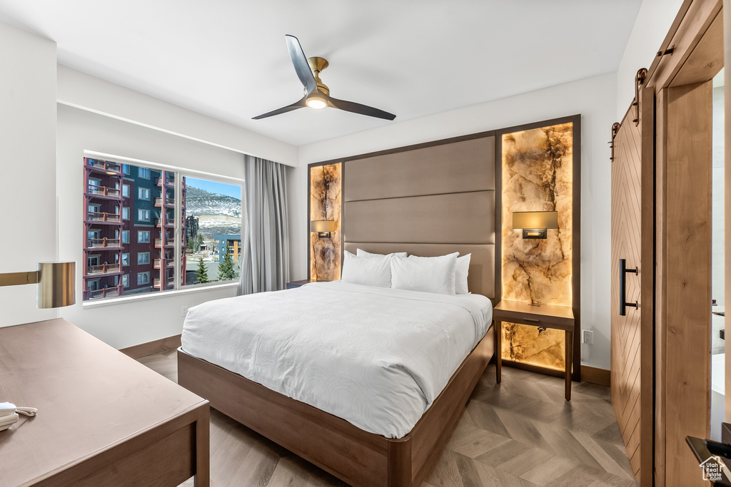Bedroom with dark parquet floors and ceiling fan