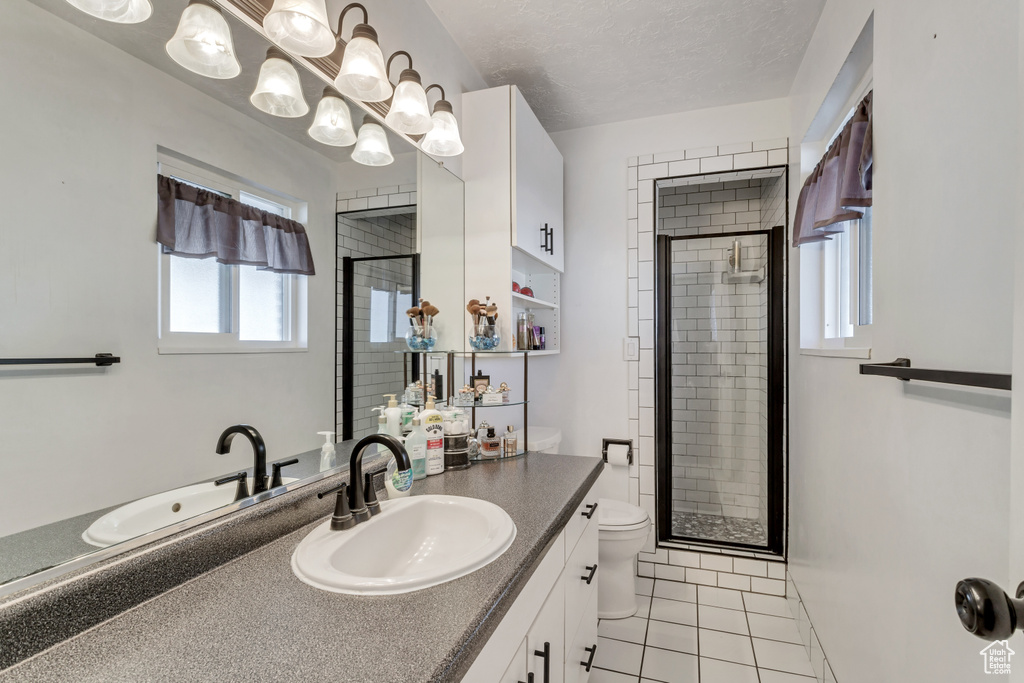 Bathroom with an enclosed shower, tile floors, large vanity, toilet, and a textured ceiling