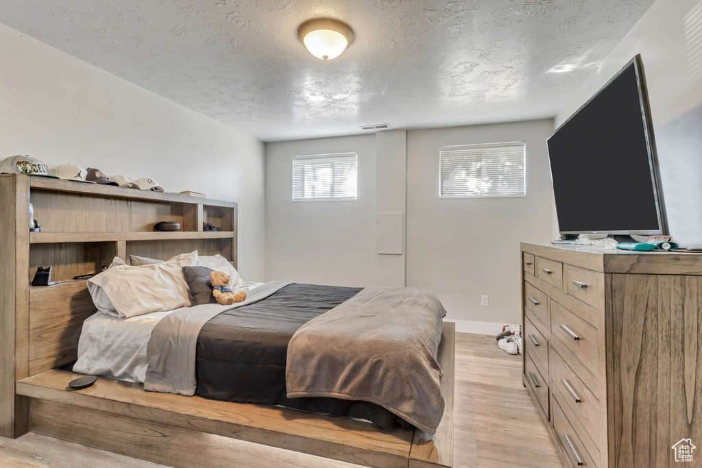 Bedroom with light hardwood / wood-style flooring and a textured ceiling