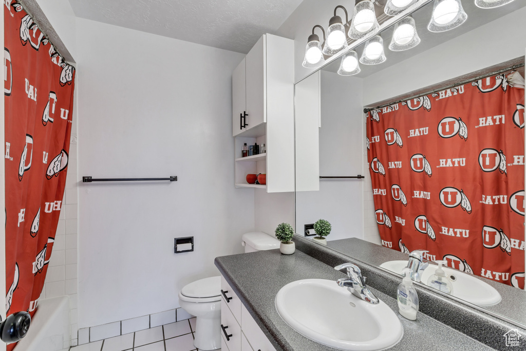 Full bathroom featuring shower / tub combo, toilet, a textured ceiling, vanity, and tile floors