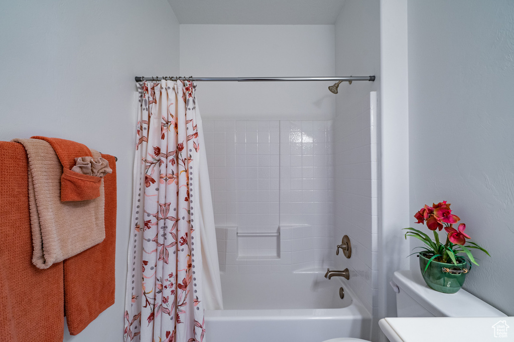 Bathroom featuring shower / bathtub combination with curtain and toilet