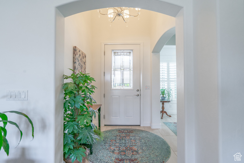 Foyer entrance with a notable chandelier and light tile flooring