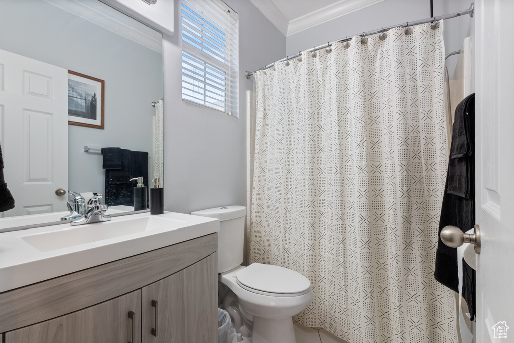 Bathroom with large vanity, crown molding, and toilet