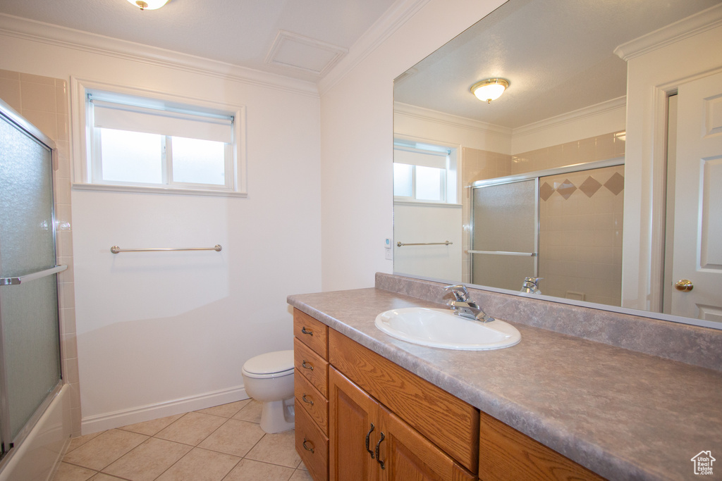 Full bathroom with vanity with extensive cabinet space, shower / bath combination with glass door, ornamental molding, tile flooring, and toilet