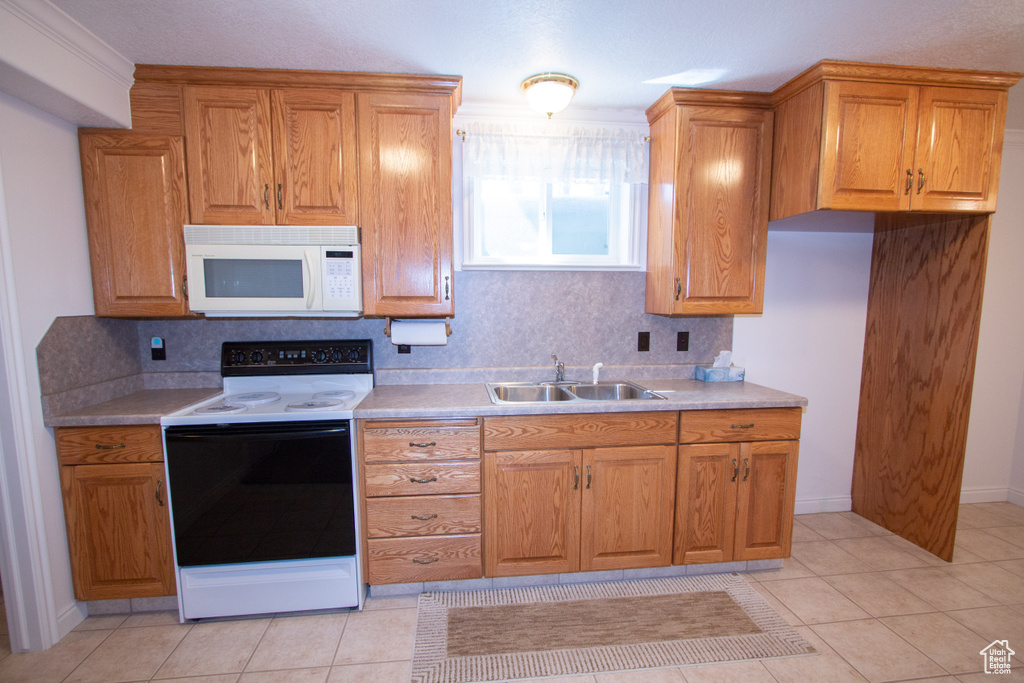 Kitchen with backsplash, white appliances, sink, and light tile floors