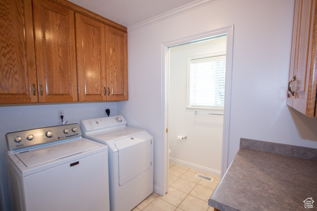 Laundry room with cabinets, separate washer and dryer, crown molding, electric dryer hookup, and light tile floors